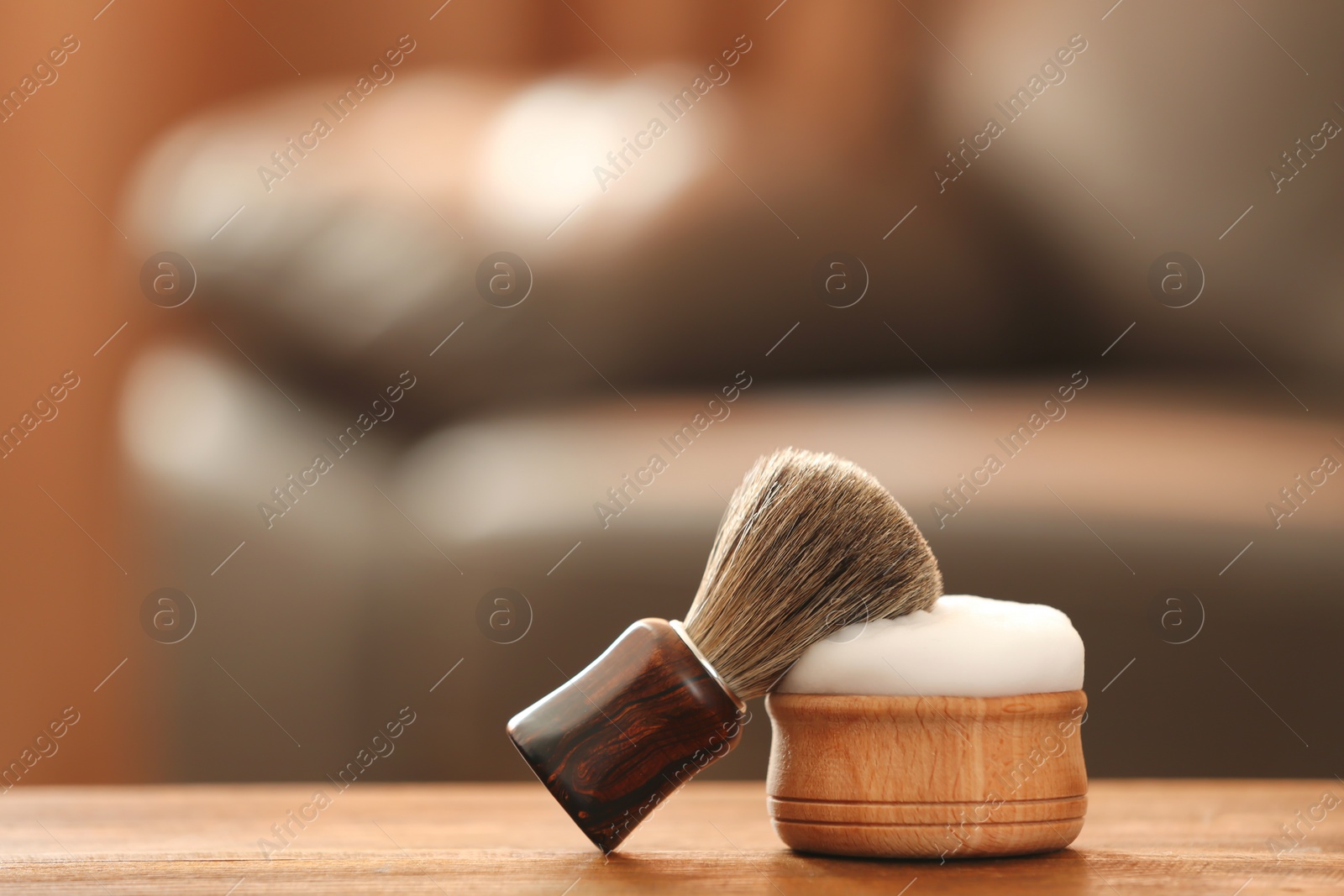 Photo of Shaving brush and foam on table against blurred background with space for text