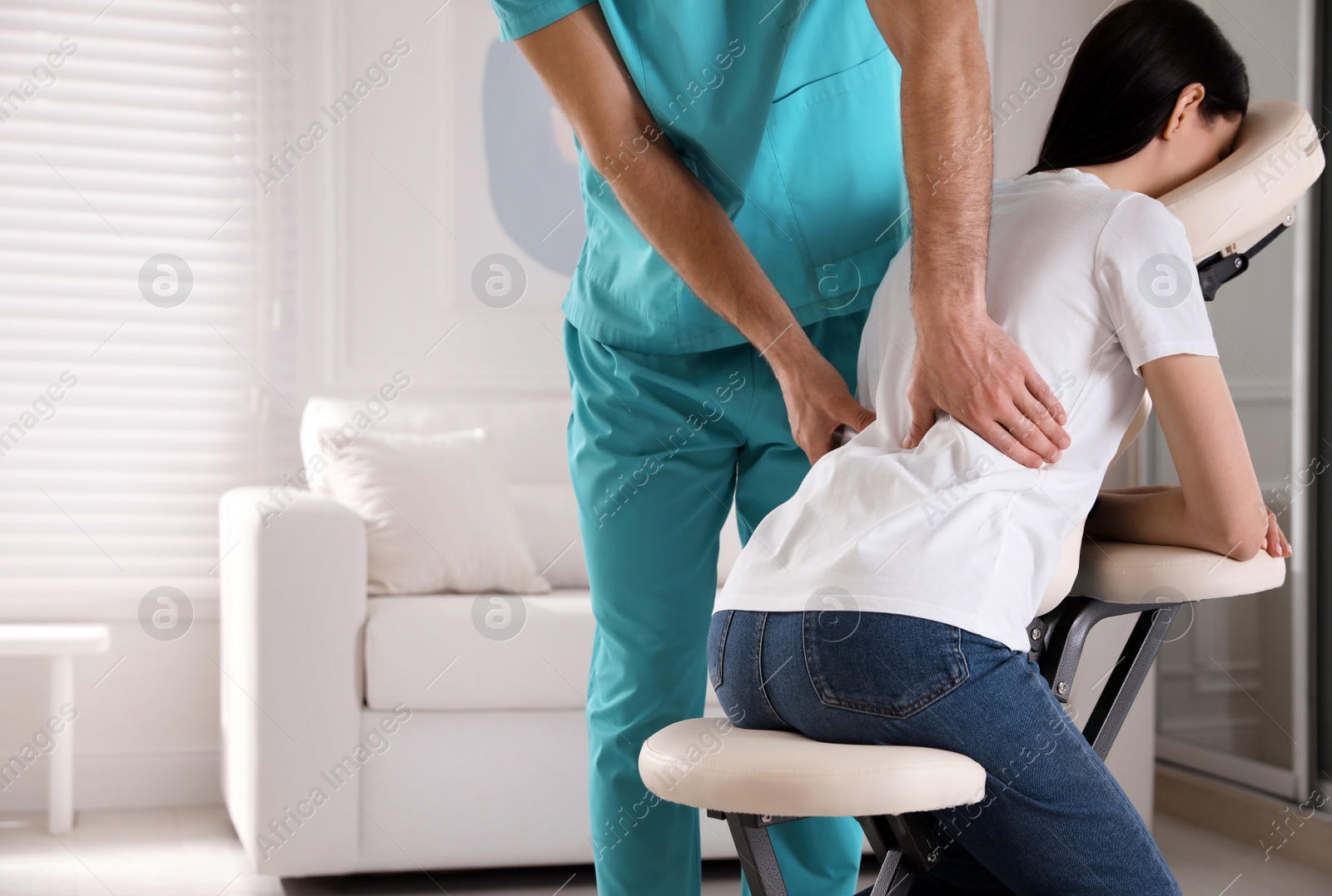 Photo of Woman receiving massage in modern chair indoors