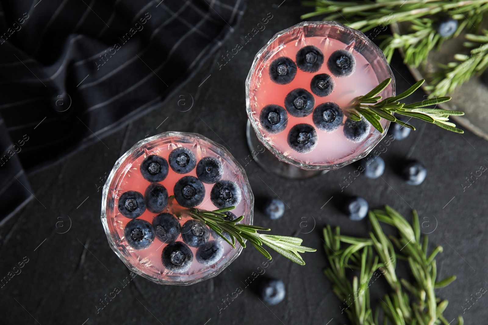 Photo of Flat lay composition with glasses of blueberry and rosemary cocktail on dark table