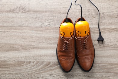 Photo of Pair of stylish shoes with modern electric footwear dryer on wooden background, top view. Space for text