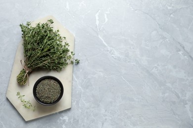 Photo of Bowl with dried thyme and fresh herb on light table, top view. Space for text