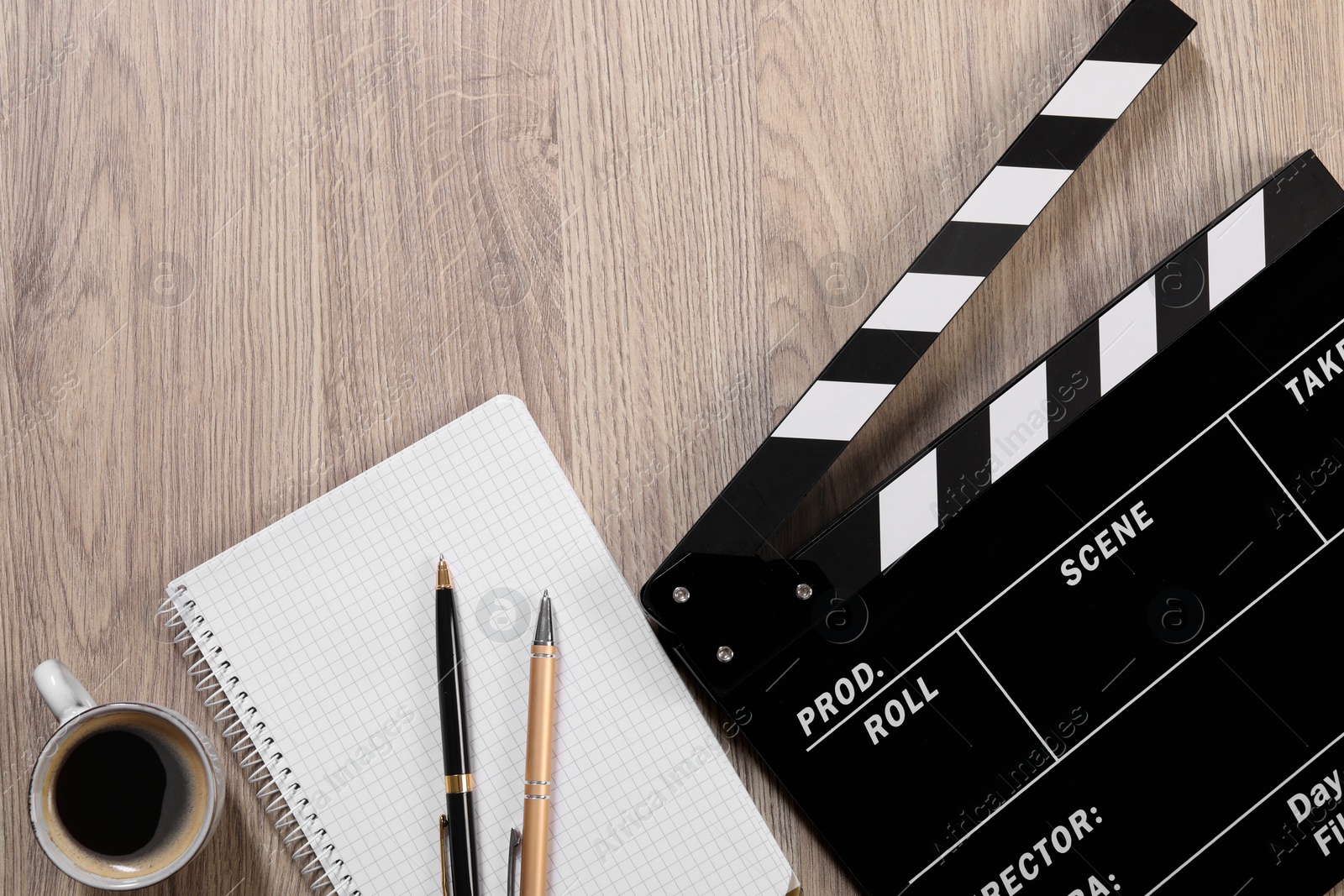 Photo of Movie clapper, notebook, coffee and pens on wooden table, flat lay. Space for text