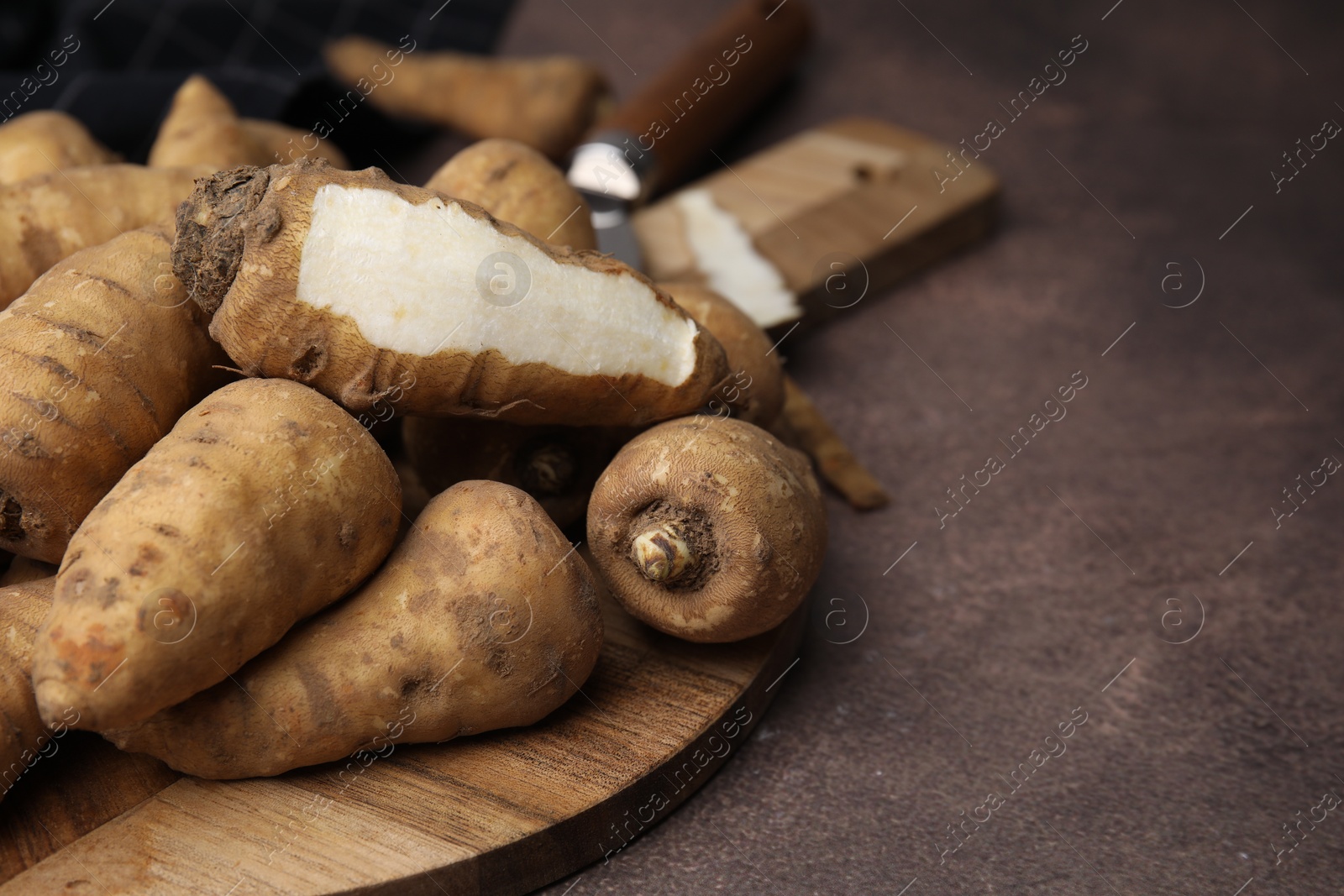 Photo of Tubers of turnip rooted chervil on brown table, closeup. Space for text