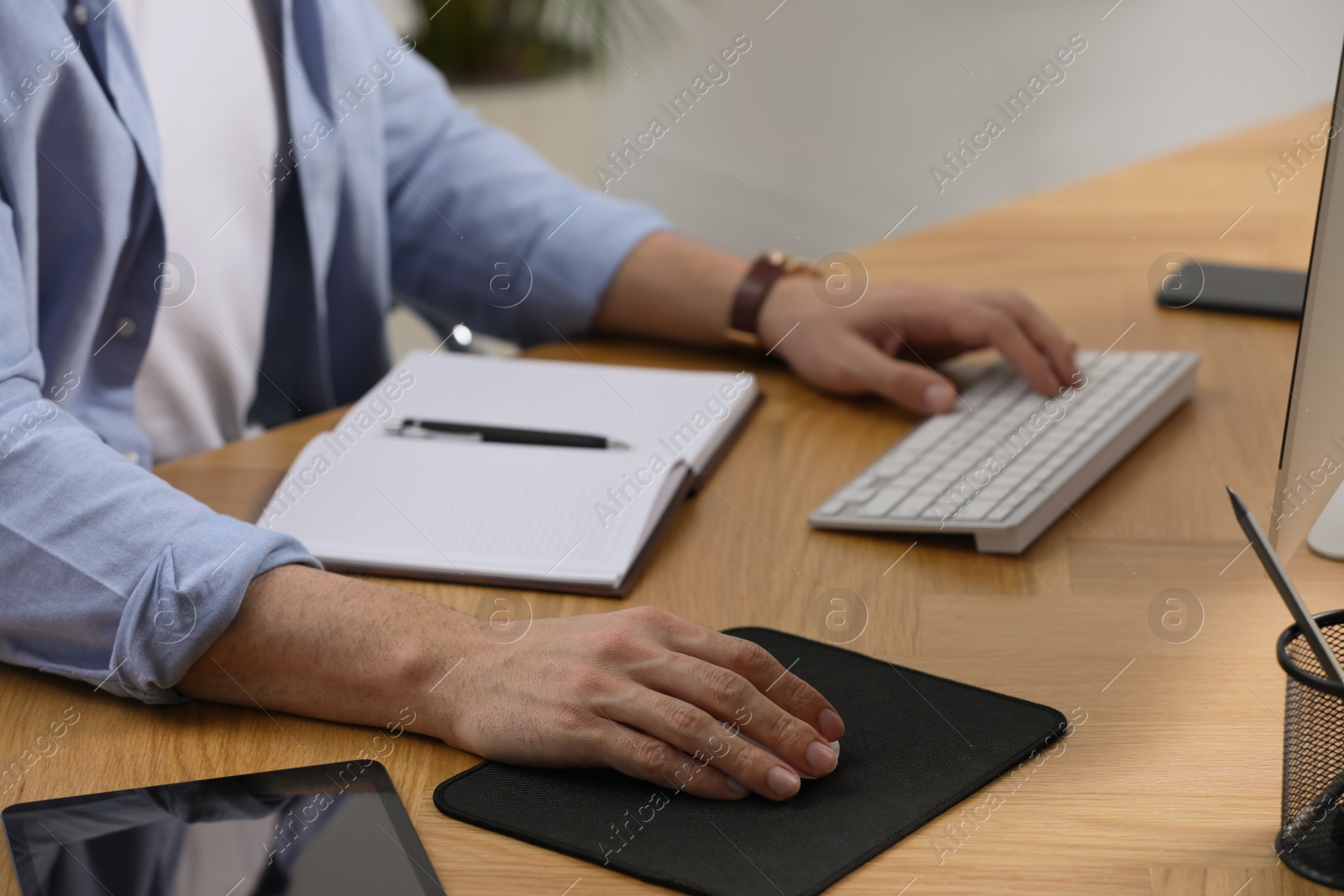 Photo of Man working on computer at table in office, closeup