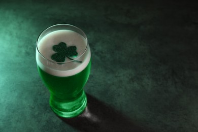 Photo of St. Patrick's day celebration. Green beer with decorative clover leaf on grey table. Space for text