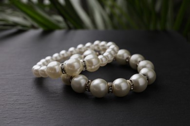 Photo of Elegant pearl bracelets on black table, closeup