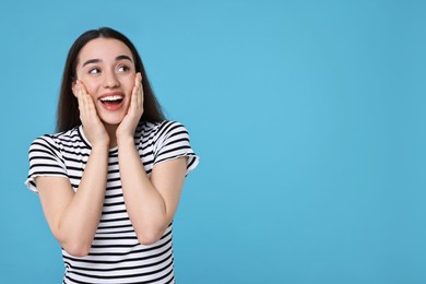 Photo of Portrait of happy surprised woman on light blue background. Space for text