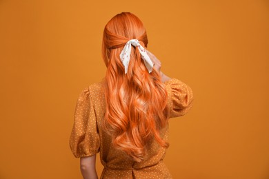 Image of Beautiful woman with long orange hair on color background, back view