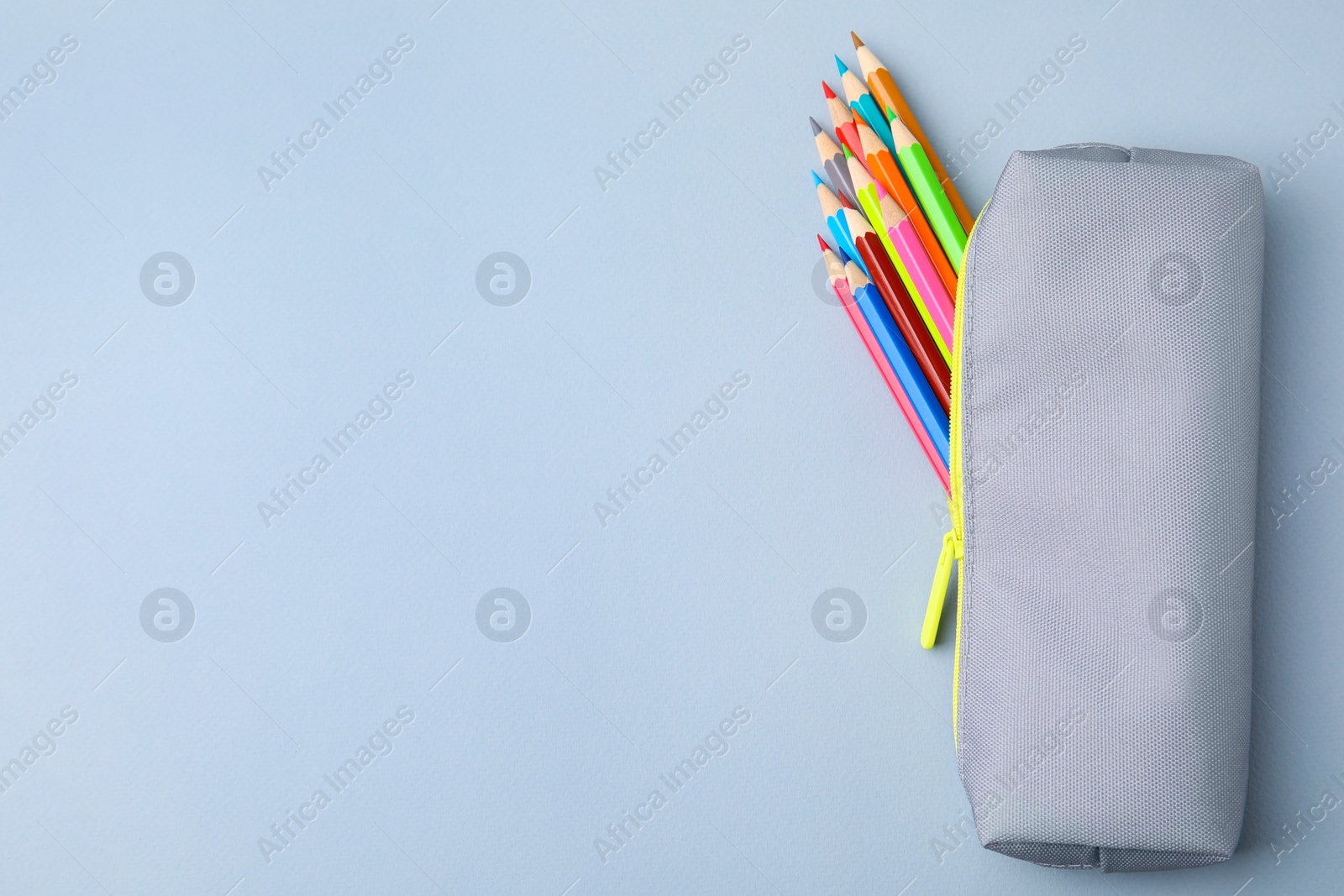 Photo of Many colorful pencils in pencil case on light grey background, top view. Space for text