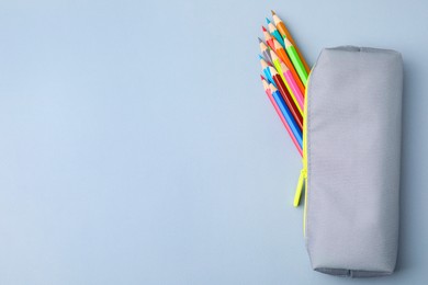 Photo of Many colorful pencils in pencil case on light grey background, top view. Space for text