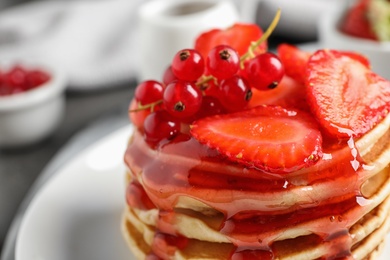 Photo of Delicious pancakes with fresh berries and syrup on table, closeup