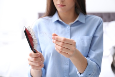 Young woman with brush indoors, closeup. Hair loss problem