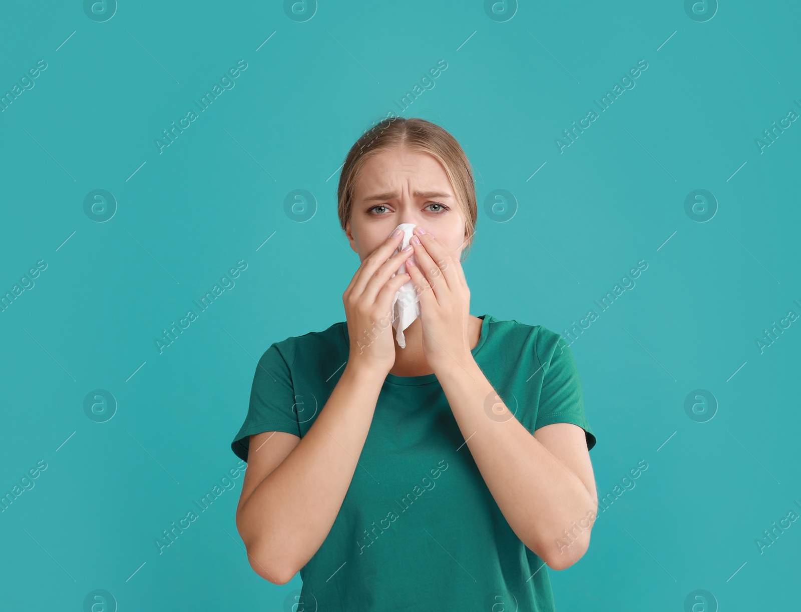 Photo of Young woman suffering from allergy on turquoise background