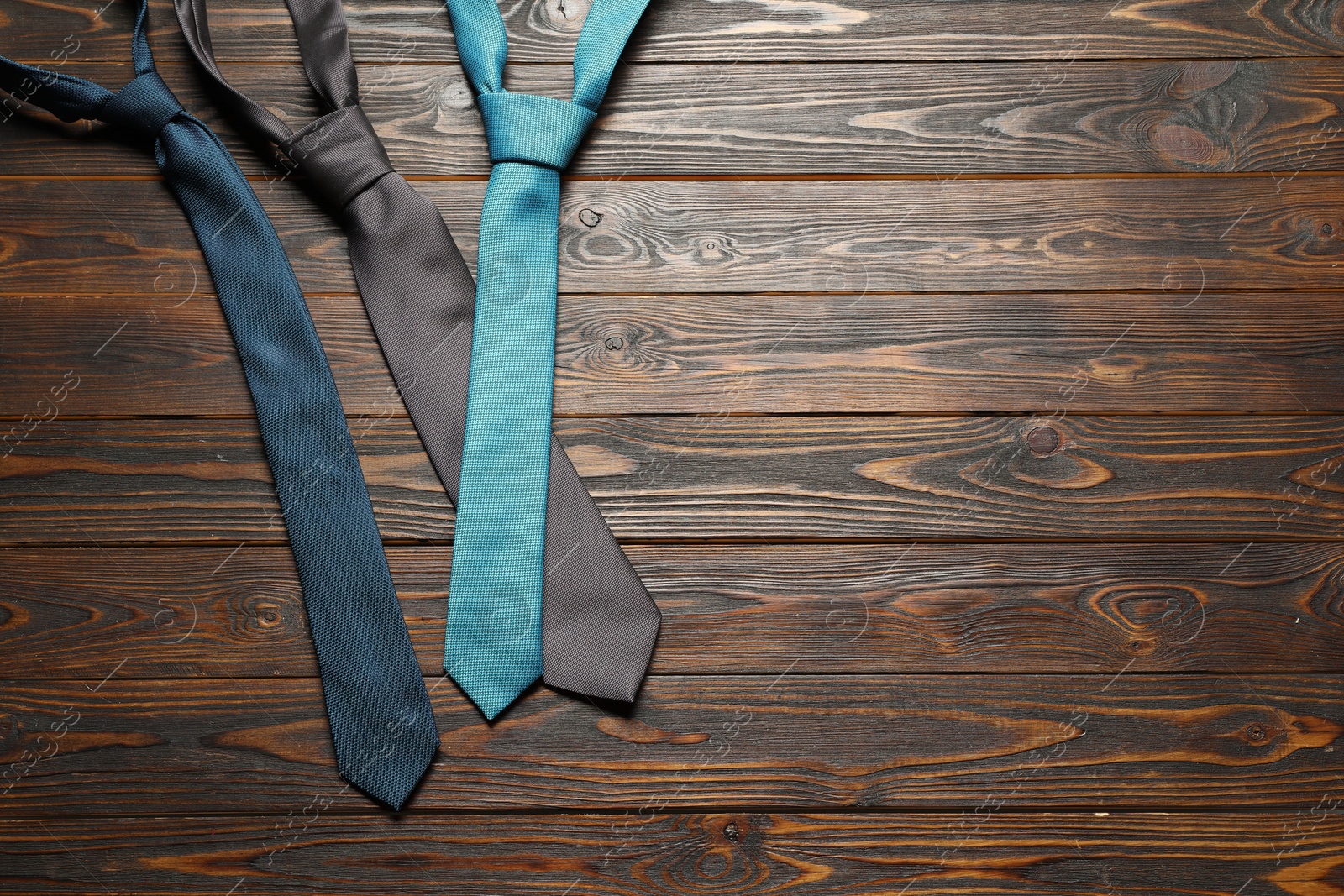 Photo of Different neckties on wooden table, flat lay. Space for text