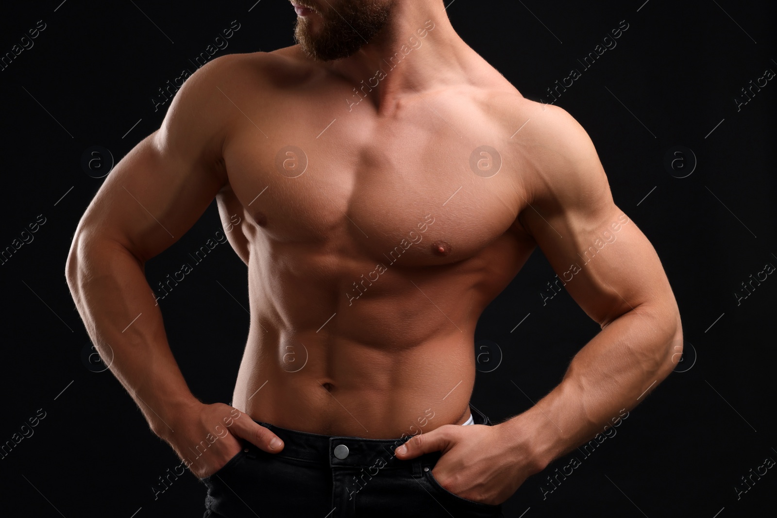 Photo of Muscular man showing abs on black background, closeup. Sexy body