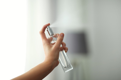Photo of Woman spraying aromatic air freshener indoors closeup