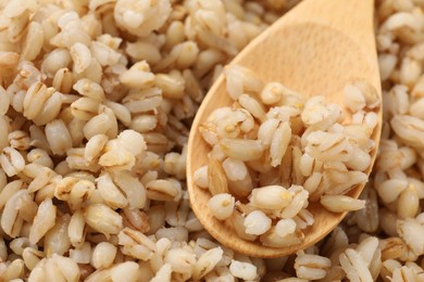 Photo of Delicious pearl barley and wooden spoon, closeup