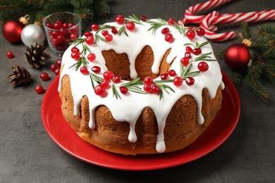 Photo of Traditional Christmas cake with cranberries, pomegranate seeds and rosemary on grey table