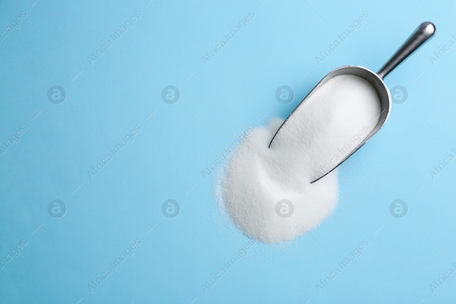 Photo of Scoop with salt on light blue background, flat lay. Space for text