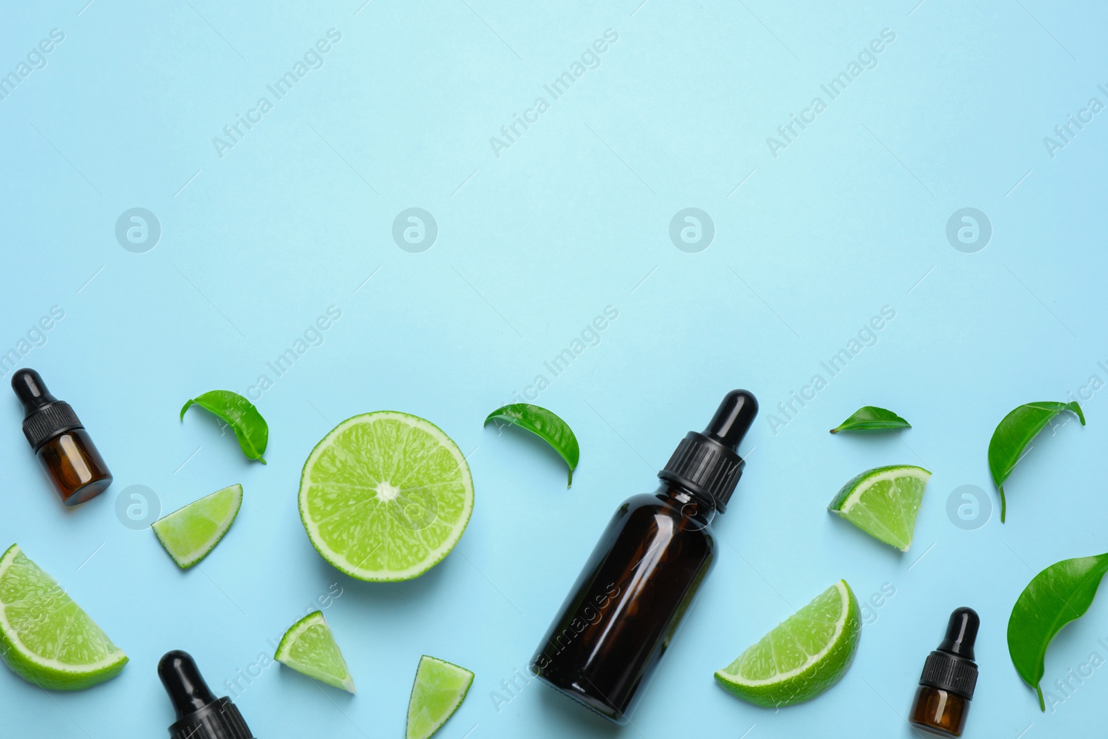 Photo of Flat lay composition with lime essential oil on light blue background. Space for text