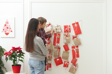 Mother and son taking gift from Advent calendar at home. Christmas tradition