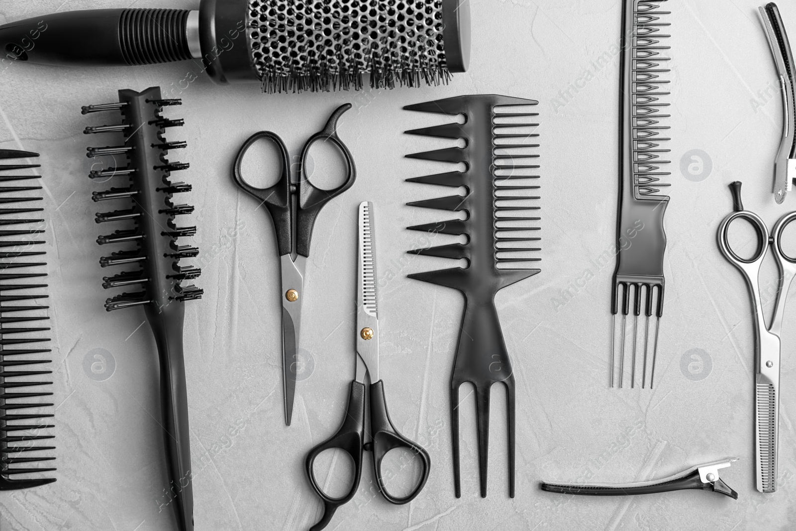 Photo of Flat lay composition with professional hairdresser tools on grey background