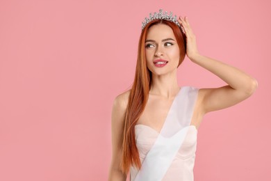 Photo of Beautiful young woman with tiara and ribbon on pink background, space for text