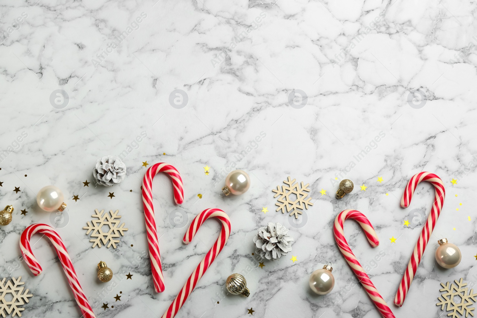 Photo of Flat lay composition with candy canes and Christmas decor on white marble table