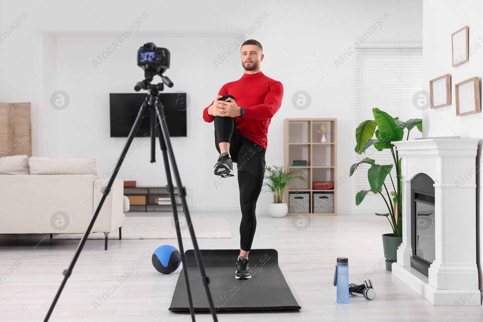 Photo of Trainer recording workout on camera at home