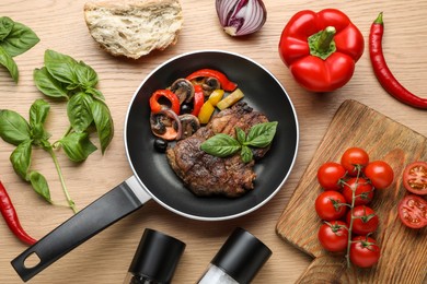 Flat lay composition with delicious steak and vegetables in frying pan on wooden table