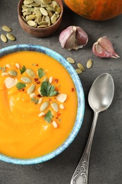 Delicious pumpkin soup in bowl on grey table, top view