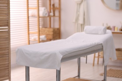 Photo of Comfortable massage table with clean towels in spa center