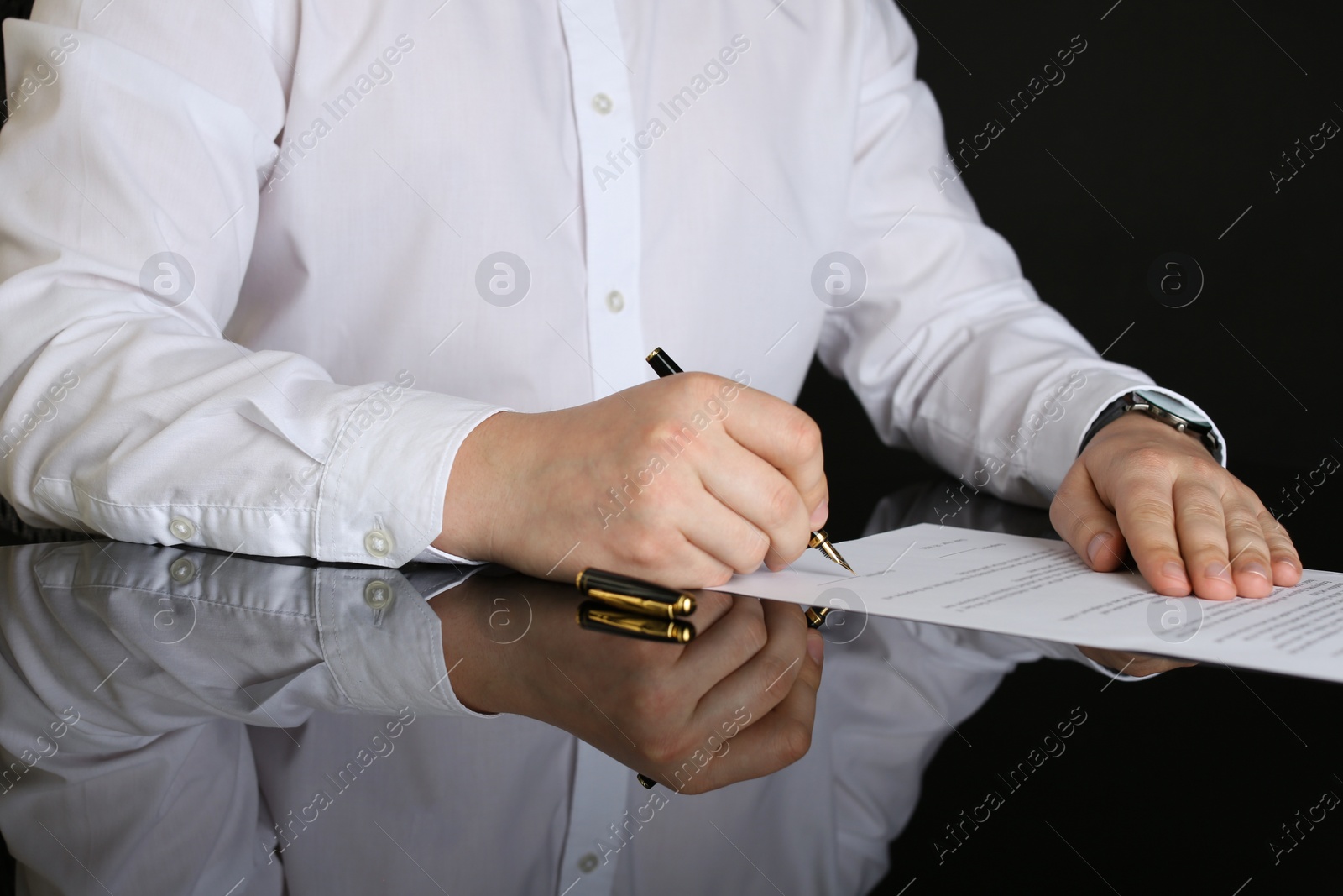 Photo of Notary signing document at black table, closeup