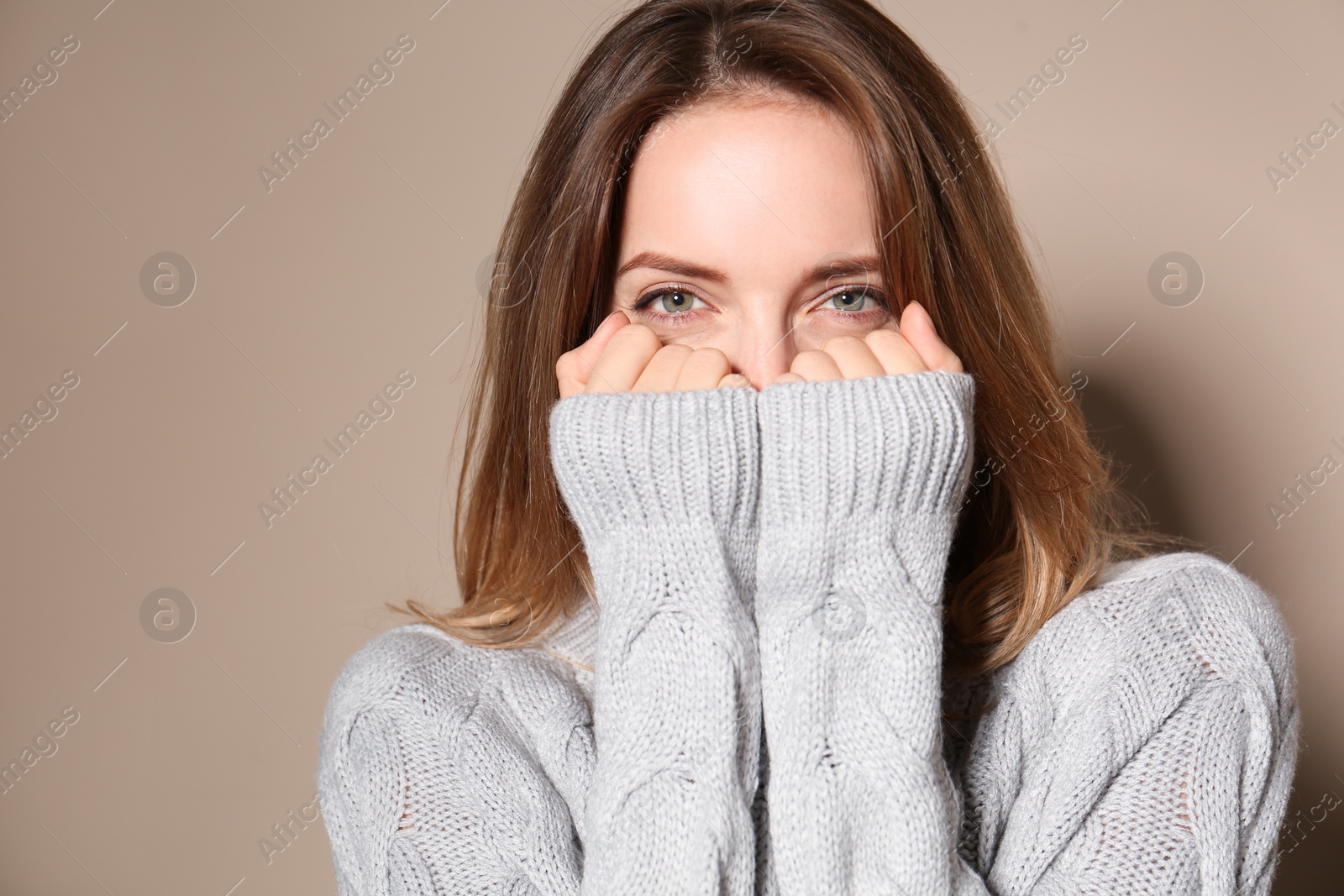 Image of Pretty young woman wearing warm sweater on beige background 