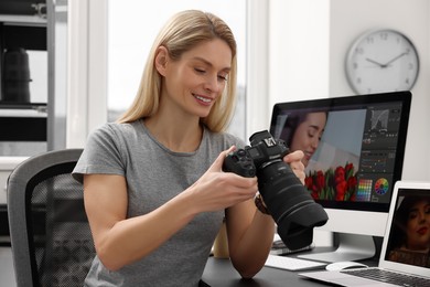 Photo of Professional photographer with digital camera at table in office