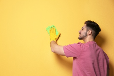 Photo of Man cleaning color wall with rag. Space for text