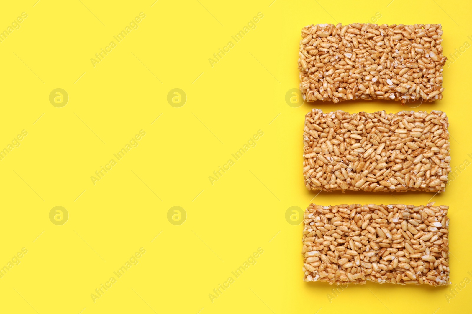 Photo of Puffed rice bars (kozinaki) on yellow background, flat lay. Space for text