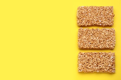 Puffed rice bars (kozinaki) on yellow background, flat lay. Space for text