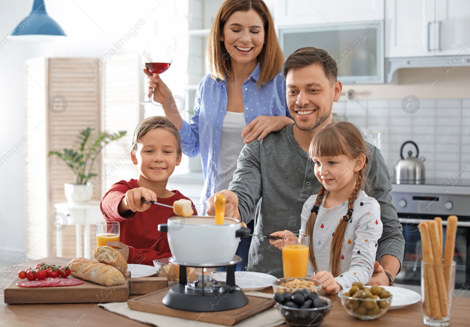 Photo of Happy family enjoying fondue dinner at home