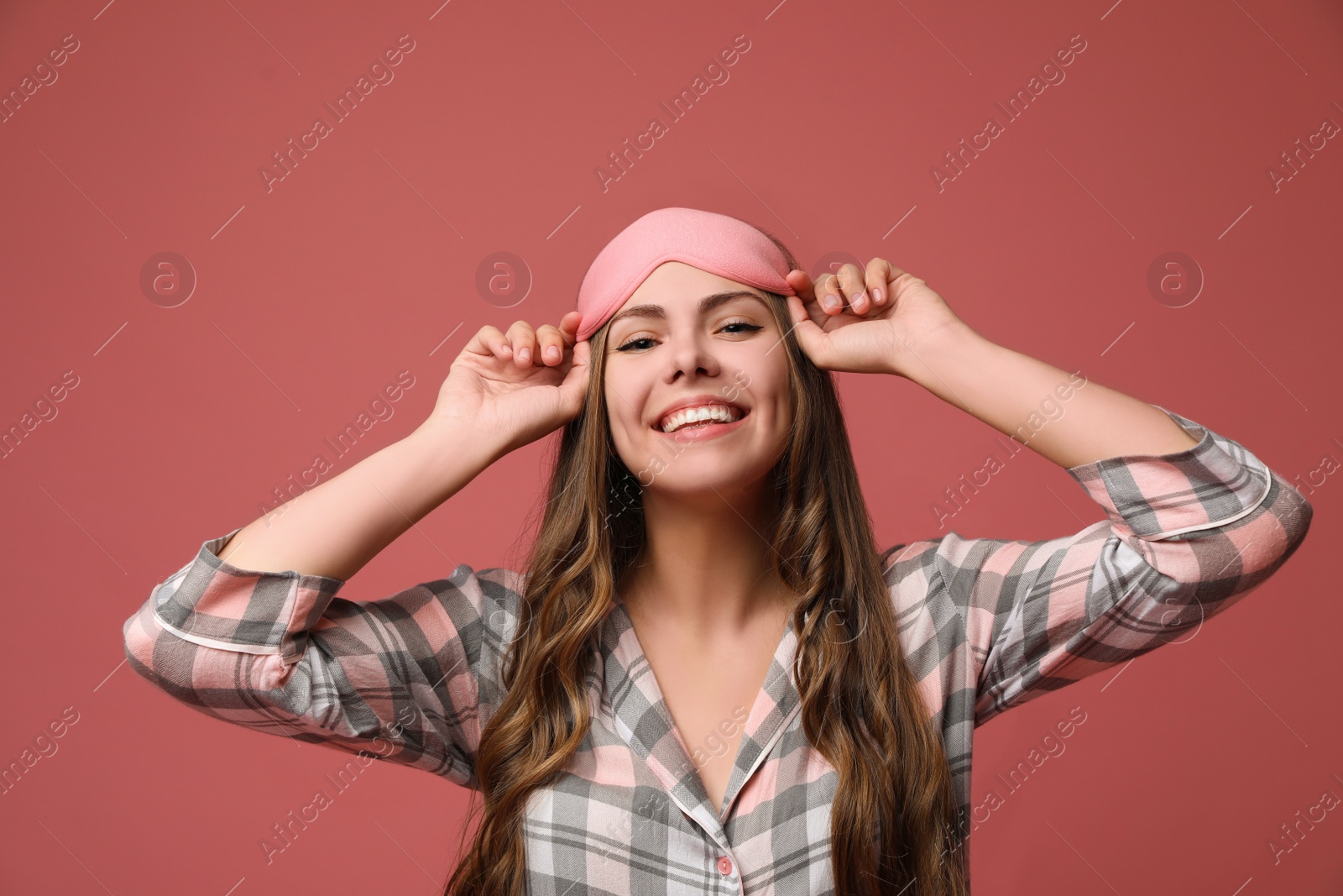 Photo of Beautiful woman wearing pajamas and sleeping mask on dusty rose background. Bedtime