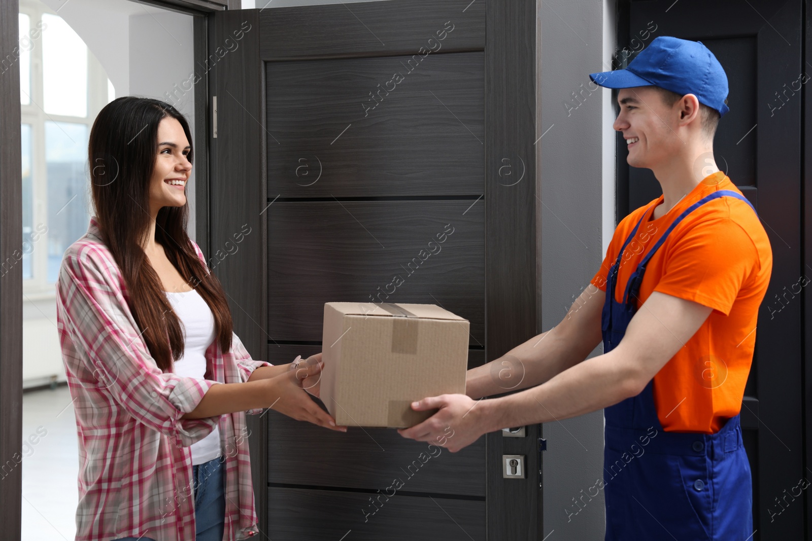 Photo of Woman receiving parcel from courier at home