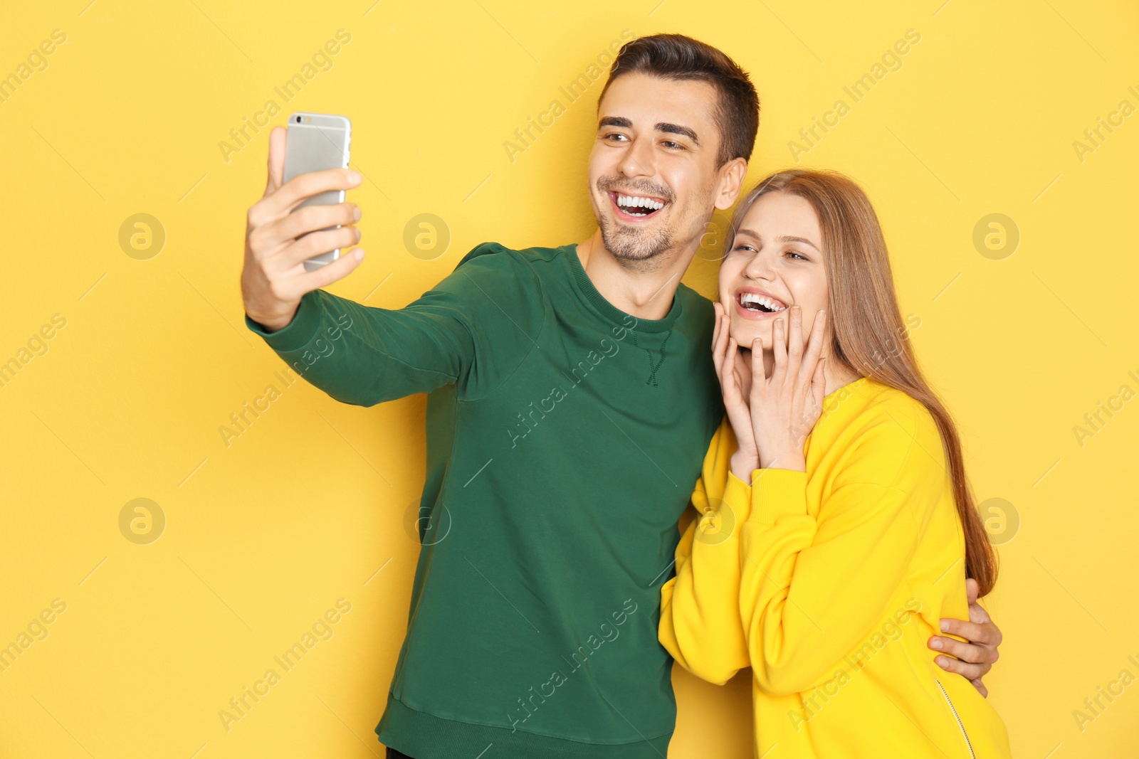 Photo of Young lovely couple taking selfie against color background