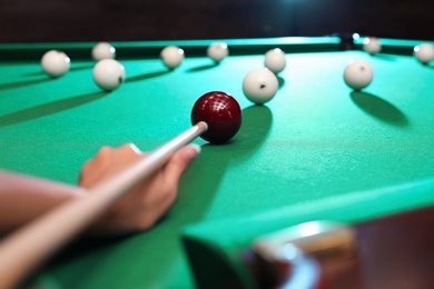 Young woman playing Russian billiard indoors, closeup