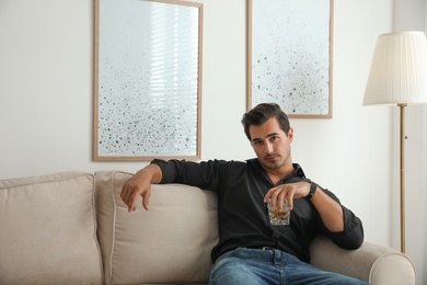 Photo of Young man with glass of whiskey at home