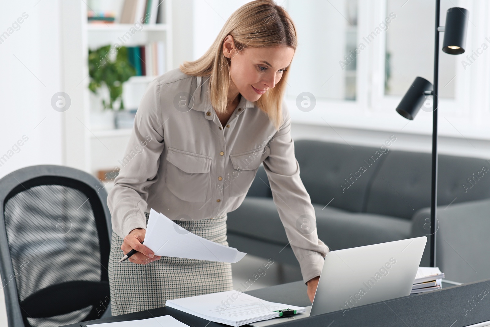 Photo of Businesswoman working with documents at grey table in modern office