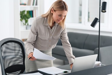 Businesswoman working with documents at grey table in modern office