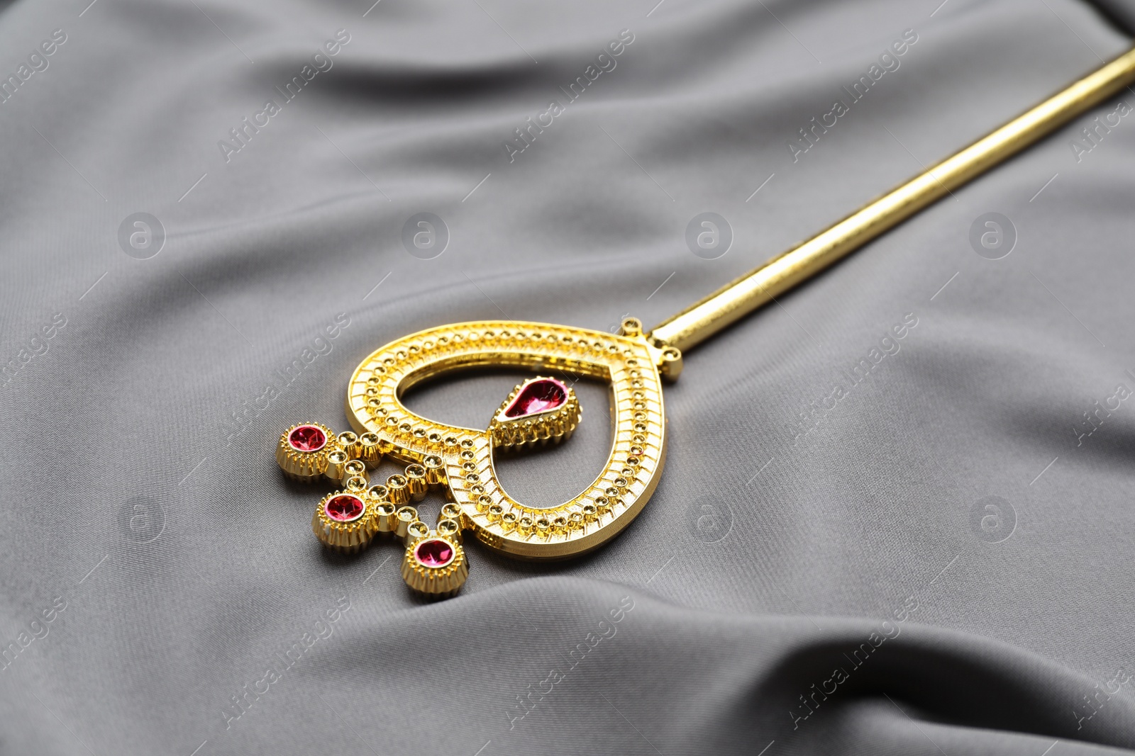 Photo of Beautiful golden magic wand on grey fabric