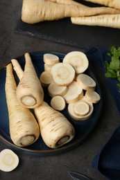 Photo of Whole and cut parsnips on black table, above view