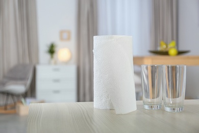 Photo of Roll of paper towels and glasses on table indoors. Space for text