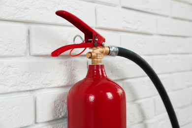 Photo of Fire extinguisher near white brick wall, closeup